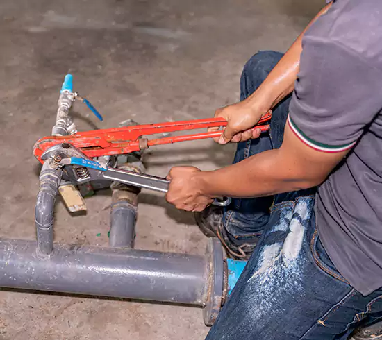 Licensed plumber repairing a copper pipe leak in a Colorado basement